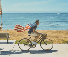 man wearing american flag riding bike with woman chasing and holding american flag