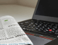 stock photo of newspaper next to laptop
