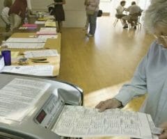 woman feeding ballot into machine