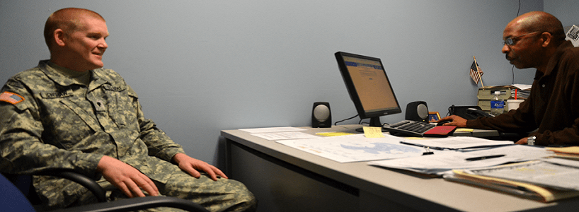 man in uniform sitting in front of man behind desk
