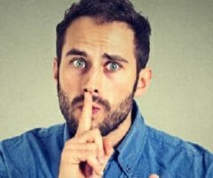 stock photo of man with finger to mouth saying shh