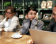 stock photo of men and women sitting at long table in coffee shop