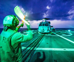 Helicopter taking off from landing pad on ship