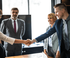 Stock photo of man and woman shaking hands over conference room table