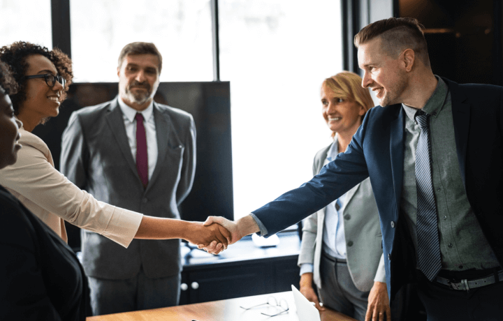 Stock photo of man and woman shaking hands over conference room table