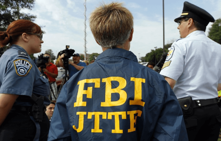 FBI and police personnel standing in front of mic and cameras