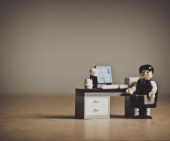 Stock photo of Lego man looking concerned at tiny desk