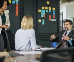 Women and man at conference table meeting and talking