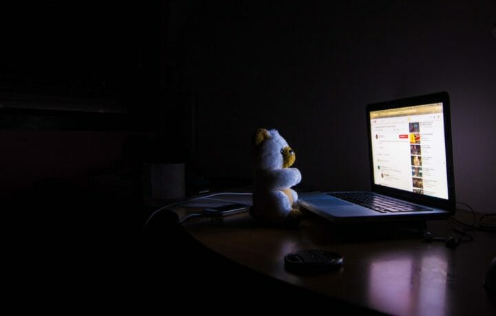 Teddy bear in front of computer in dark room