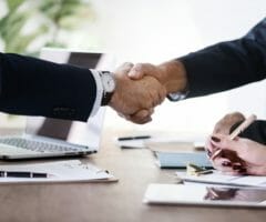 Men shaking hands over conference table