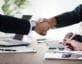 Men shaking hands over conference table