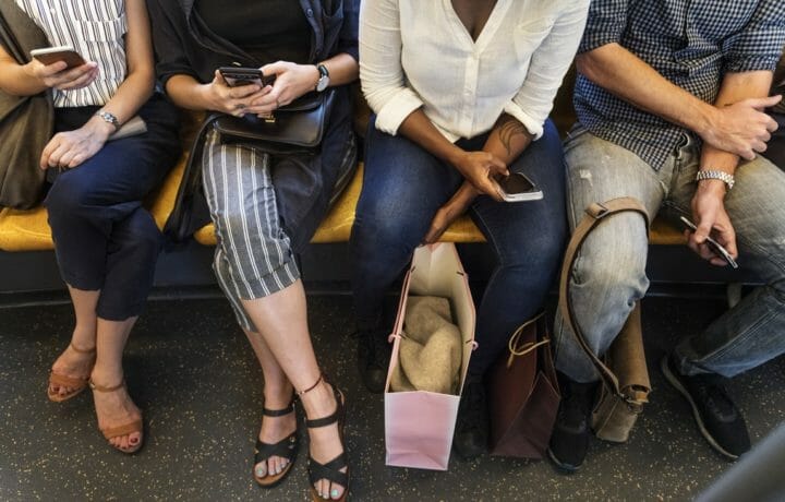 Photo of people on subway train holding phones
