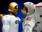 Human spacesuit and robotic astronaut facing each other