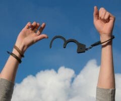Person putting hands in air with handcuffs coming off