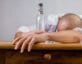 Man passed out on desk with bottle of alcohol