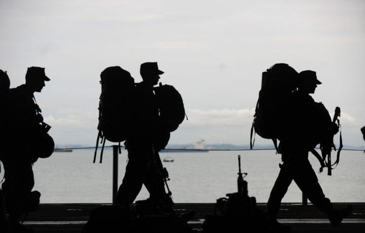 Silhouettes of three soldiers with large backpacks