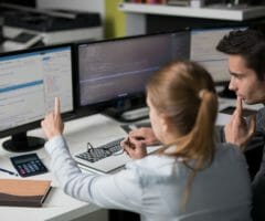 Woman and man looking at code on computer screens