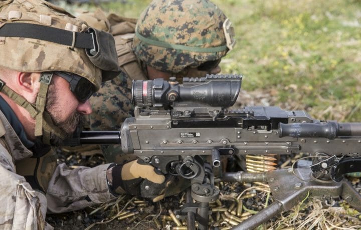 Men in uniform looking through scope on rifle