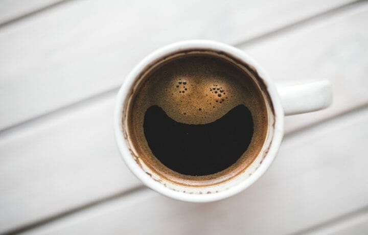 Photo of coffee mug with coffee bubbles appearing to smile