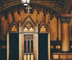 confessional booth in a catholic church two doors with dark velvet curtains and intricate woodwork