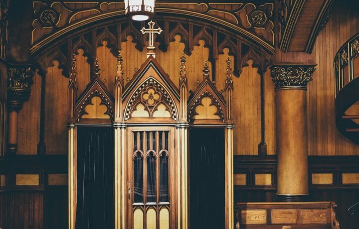 confessional booth in a catholic church two doors with dark velvet curtains and intricate woodwork