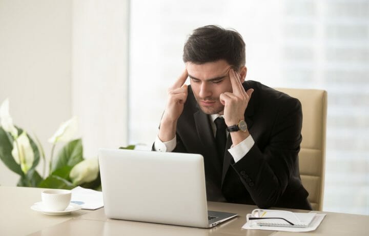 Job Serious frustrated businessman with closed eyes suffering from at desk massaging temples