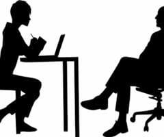 Silhouettes of woman behind desk with computer and man in office chair