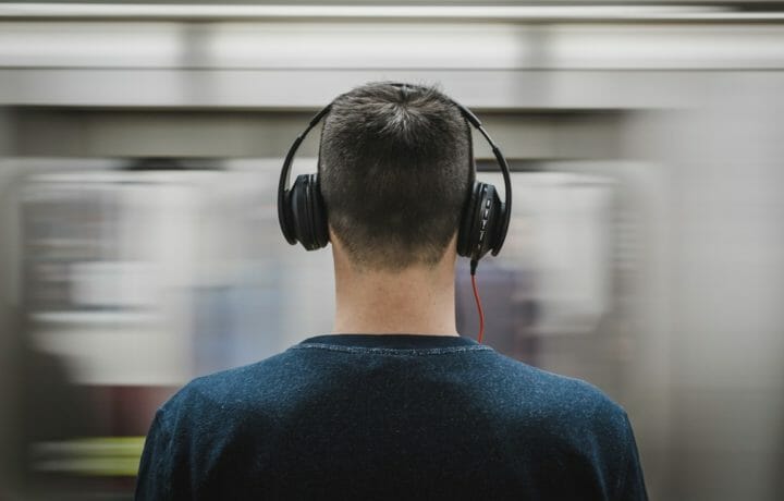 Man wearing headphones with passing subway train