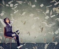 woman sitting in chair with money falling all around her
