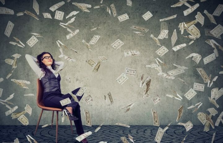woman sitting in chair with money falling all around her