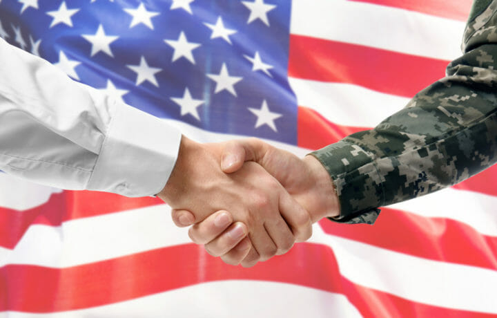 military man shaking hand of business man with american flag