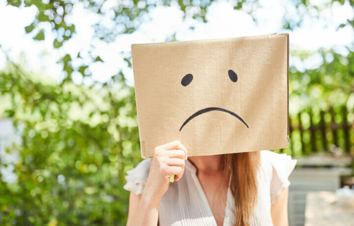 Young Woman Has Face in Cardboard Box with Sad Face