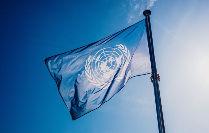 UN Flag Waved against the Sun and Blue Sky.