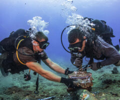 Chief Construction Electrician Daniel Luberto (right) and Construction Mechanic 3rd Class Andersen Gardner, with Underwater Construction Team 2 Construction Dive Detachment Bravo (UCT2 CDDB), remove corroded zinc anodes from an undersea cable at the Pacific Missile Range Facility Barking Sands, Hawaii on July 5, 2016.