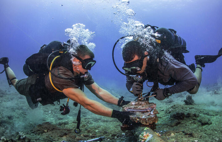 Chief Construction Electrician Daniel Luberto (right) and Construction Mechanic 3rd Class Andersen Gardner, with Underwater Construction Team 2 Construction Dive Detachment Bravo (UCT2 CDDB), remove corroded zinc anodes from an undersea cable at the Pacific Missile Range Facility Barking Sands, Hawaii on July 5, 2016.