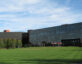 Photo of the University of Dayton Research Institute. Glass building with a green field and flags in front of the building.