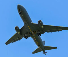 Photo of the underside of the Air Force's KC-46A Pegasus flying. The sky is a clear and bright blue.