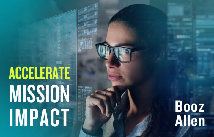 Photo of woman looking at a screen, with the screen reflected in the image. The words "Accelerate Mission Impact" are in the bottom left, and in the bottom right it says "Booz Allen."