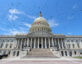 Photo of the Capitol against a blue sky with birds flying.