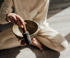 Photo of a person sitting cross-legged with a singing bowl
