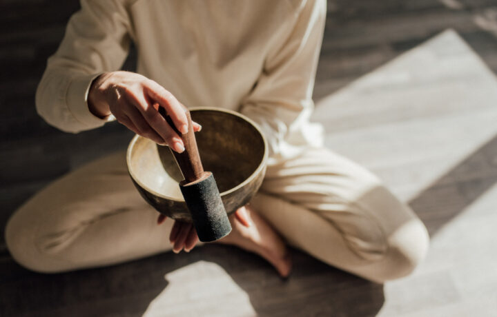 Photo of a person sitting cross-legged with a singing bowl