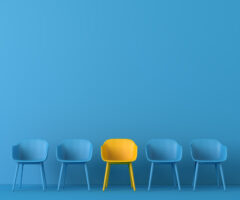 Image of blue chairs against a blue background, but in the middle is a yellow chair.