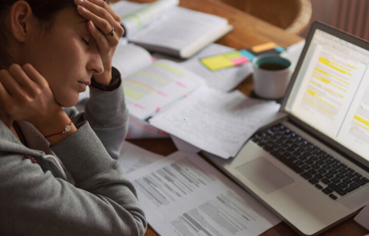 worker with hand on head in front of a computer