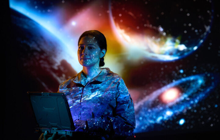 Photo of a female service member with space projections in the background.